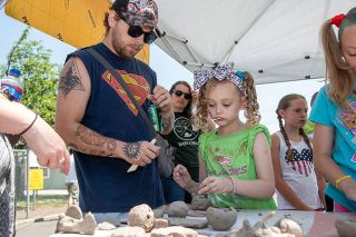 Rusty Rae/News-Register##Athena Marler, 6, of Willamina, puts her artistic ability to work at the East Creek Kids’ Clay Day, a first-time activity at the Willamina Old Fashioned Fourth of July Celebration. Looking on is her father, Michael Marler.