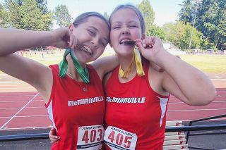 Submitted Photo##Serenity Chung and Brooke Johnston bite their medals after qualifying for the National Junior Olympic meet in Eugene next week. They will both be participating in hammer and discus, and Johnston will also throw in javelin.