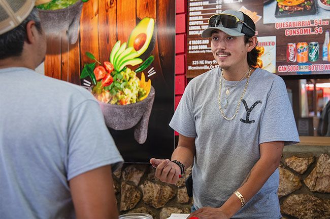 Rusty Rae/News-Register##Ray Loera, manager, serves a customer at Tacos el Gordo stand, one of three businesses at 325 N.W. Highway 99W owned by his dad, Rodrigo “Rudy” Loera. The taco stand is next to the restaurant Tequila Grill and the new Azteca Market, which offers produce and Mexican products.