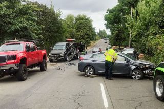 Kirby Neumann-Rea/News-Register##Operator Chris Paola of Gale s Towing & Recovery checks a vehicle as he prepares to tow it from the scene Aug. 29 on Southwest Adams Street, one of two rollover accidents in the past week.