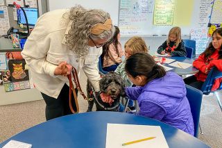Starla Pointer/News-Register##Third-grader Natalie Rodriguez pets Minnie Lei as retired teacher Judy Suan walks her service dog through Paige Petersen’s classroom at Willamette Elementary School. Minnie is trained to help her owner remain calm and steady. Suan previously taught at Newby Elementary, where she brought her earlier service dog, Tonka, to classes.