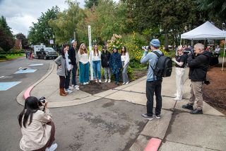 Rusty Rae/News-Register##Photographers take pictures of Linfield’s new peace pole surrounded by some of the university’s international students. The pole says “May Peace Prevail on Earth” in eight languages; students added more out loud during the dedication ceremony.