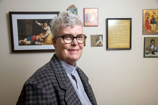 Rusty Rae/News-Register##St. Barnabas Church leader Cathy Clark in her office, where walls are covered with religious images. “I’m always Cathy,” she said. “I’m a friend, a sister, a golfer, a Rotarian, a cat lover … and a priest.”