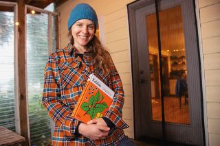 Rusty Rae/News-Register##Katie Kulla holds her first book, a volume she illustrated with more than 150 drawings. She worked on “Edible” with a pair of authors from England and Austria.