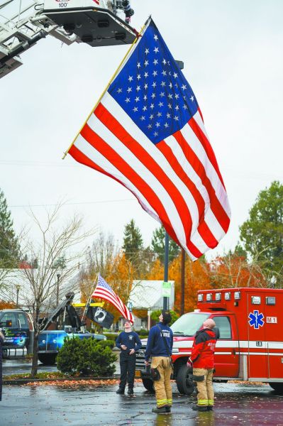 Rachel Thompson/News-Register##McMinnville firefighters Jimmy Clark, Tiger Robitaille and Steve Zimmerman respectfully lower a large American flag following the parade.