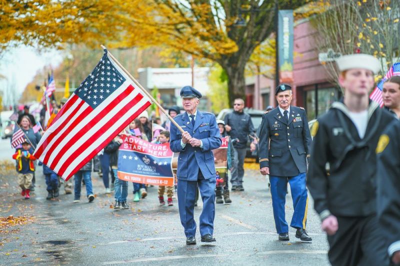 Rachel Thompson/News-Register##Air Force Capt. Al Peirish waves the flag as he walks down Third Street beside Army Lt. Col. Mike Becker in the Veterans Day parade on Saturday.
