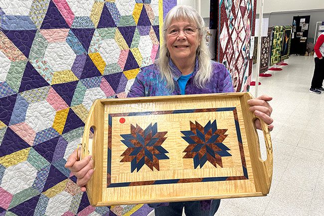Kirby Neumann-Rea/News-Register##Coastal Hills Quilters founder Cris Darr of Willamina holds up a tray made by her late husband, George. The Rock Candy pattern is made using Kewazinga, curly maple and dyed poplar in a white oak frame. Kirby Neumann-Rea/News-Register
Coastal Hills Quilters founder Cris Darr of Willamina holds up a tray made by her late husband, George. The Rock Candy pattern is made using Kewazinga, curly maple and dyed poplar in a white oak frame.