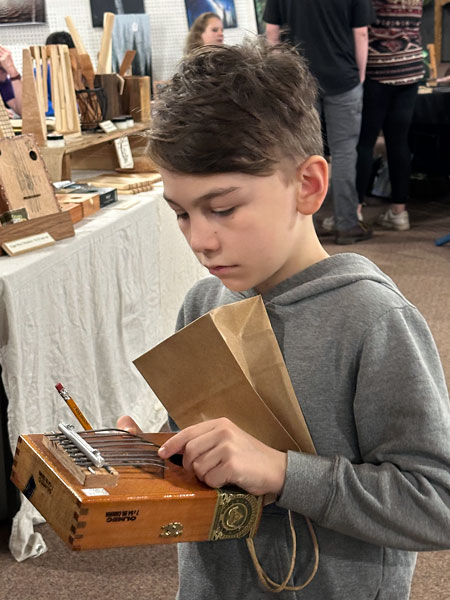 Kirby Neumann-Rea/News-Register##Kalakoa Riggs-Napoleon, 8, of Willamina, plucks notes on his kalimba, newly-purchased from woodworker and cigar-box ukelele maker Will Eikleberry of McMinnville, at Free Methodist Church, among the stops on the Art Tour.