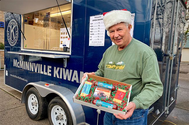 Starla Pointer/News-Register##Kiwanis Club member Roger Fowler shows off one of the cheese, sausage and fudge gift packs sold to raise funds for scholarships and youth activities. The Kiwanis cheese wagon is parked at Third and Davis streets.