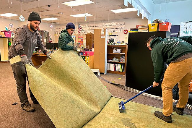 Kirby Neumann-Rea/News-Register##In January, Vlad Tarashuk, left, Paolo Samchuk and David Leonchik of Rapid Response Restoration & Construction pull and scrape to remove damaged carpeting from a Grandhaven classroom.