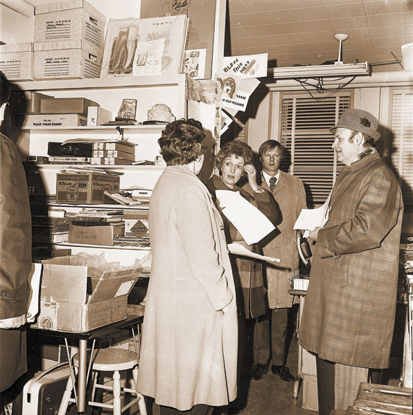##(Jan. 12, 1974) “Bless our mess” is sincere sentiment in storeroom visited during junior high school tour. Left to right are Luella Heringer, member of the board; budget committee members, Eleanor Macy and Bob Smith; and Superintendent Orval Ause. [Site of school now Baker Street Square]