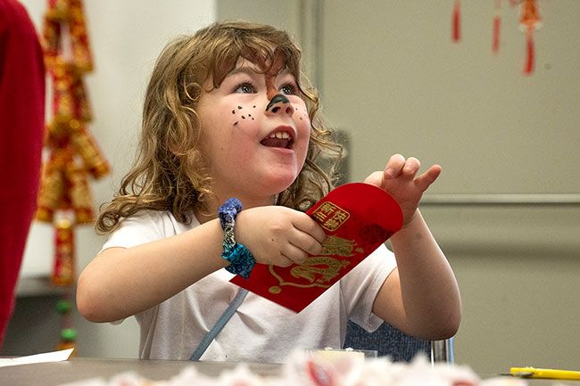 Rachel Thompson/News-Register##Stella Wismer, 4, of Gaston, is excited to discover a dollar bill inside a red packet given to her at the Lunar New Year celebration. The dollars were a donation from Lum’s GMC, one of the sponsors of the event.