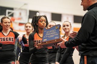 Rachel Thompson/News-Register##Yamhill Carlton’s Tiearra Braithwaite hands YC’s first cheer trophy to athletic director Brad Post on Friday, Feb. 16 in an assembly.