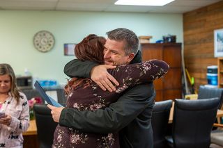 Rachel Thompson/News-Register##Award in hand, Kyle Johansen accepts a congratulatory hug from Kari Smith, a member of the marketing team, in the surprise event at Provoking Hope.