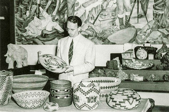 Image: UO Libraries##Luther Cressman inspects an Indian basket from a collection at the UO Museum of Natural History in 1937, when the museum was still located on the second floor of Condon Hall. The museum, which Cressman founded, has moved to its own building and has been renamed Museum of Natural and Cultural History.