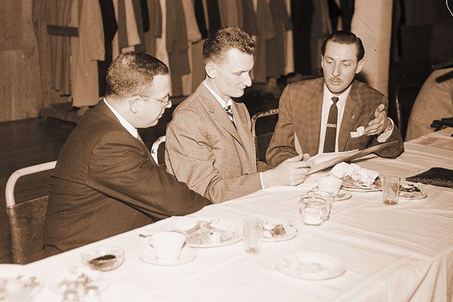 ## (Feb. 26, 1959) Secretary of State Howell Appling Jr., (center) goes over his speech with Harold Heller (left) and Norris Johnson prior to his talk at the annual Farmer’s Night banquet Tuesday night. Appling spoke to an audience of 200 farmers and businessmen. Heller served as program chairman for the banquet sponsored by the Farm Implement Dealers association of the McMinnville Chamber of Commerce. Johnson is manager of the chamber.