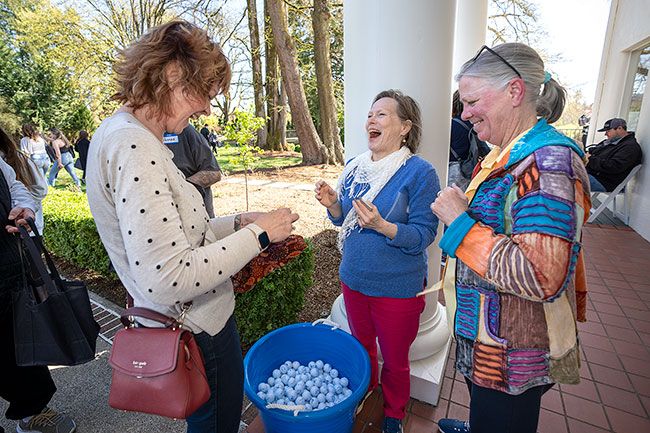 Rachel Thompson/News-Register##Heidi Vollmer, left, turns in her golf ball “egg” to see if she’s won a prize during McMinnville’s first adult Easter egg hunt. Patty Williams, right, director of the Willamette Valley Cancer Foundation, which sponsored the fundraising event, celebrates her win, as does volunteer Kris Wessel, center.