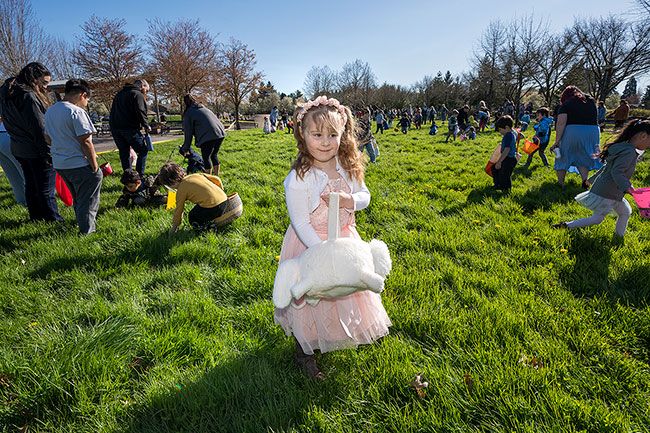 Rachel Thompson/News-Register##Alice Rowe, 4, maintains an air of calm as children around her race to find eggs in the lush grass at Discovery Meadows Park during the annual Lions Club Easter egg hunt Saturday morning.
