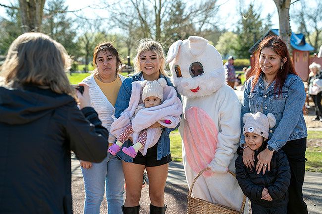 Rachel Thompson/News-Register##Mac High sophomore Mallorie Crabtree, a member of the Leo Club junior Lions group, photographs a McMinnville family, from left are Araceli Estrada, Ari Ceras, holding baby Maylin Moreno, Easter Bunny and Leo member Elsie Best, and Diana Ceras, standing with Emmeline Moreno.