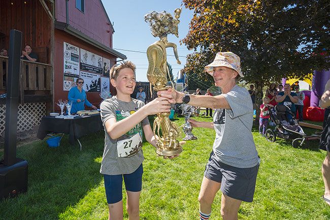 Rachel Thompson/News-Register##Julian Johnston, 11, of Tigard, left, receives a trophy from Yamhill Downtown Association board member Jenny Morrison, after winning the 10K race during Beverly Cleary Day. Trophies were handmade by members of the association, which sponsored the event.