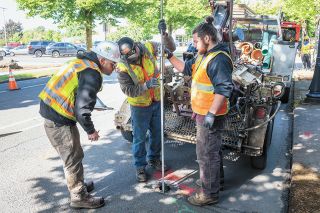 Rusty Rae/News-Register##Team from Dan Fisher Excavating uses a gauge to take soil measurements to determine what’s under the street, as part of Third Street redevelopment preparations. From left are Tyler Merlin, Harley Aldrich, Tyler Jensen and Jacob Herb.