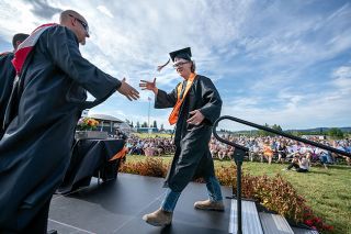 Rachel Thompson/News-Register##As he steps up for his diploma, Yamhill Carlton High School graduate Hunter Waibel shakes hands with vice principal Brad Post before a large crowd at YCHS field.