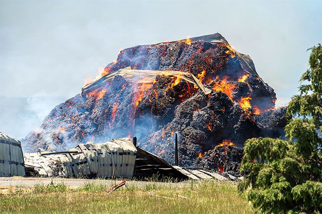 Rachel Thompson/News-Register##Melting pieces of the Sunrise Trading barn stretch across what looks like blackening lava as flames consume hay in this photo taken shortly after noon Tuesday. Firefighters planned to remain on scene for least two days to monitor the fire.