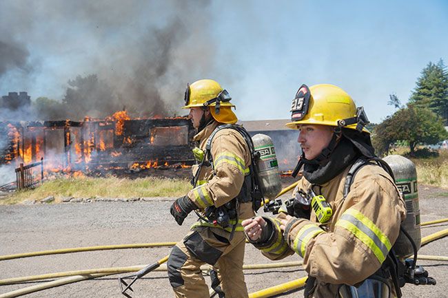 Rachel Thompson/News-Register##Aaron Martinez, left, and Bradley Wooldridge, both from McMinnville Fire District, participate in their first practice burn. Crews got an early start, gathering at 7:45 a.m. and staging first room-by-room attacks at around 8:30.