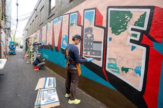 Rachel Thompson/News-Register##Colt Bowden, foreground, fills in an L with the image of Buchanan Cellers granary Thursday as he and friends work on the first mural in McMinnville’s new art alley. Bowden, of Gold Hand Signs of McMinnville, said he had been dreaming of creating a postcard with iconic images; now he’s doing one on a giant scale.