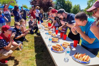 Starla Pointer/News-Register##Counters and other community members watch contestants chow down on hot dogs in buns at Lafayette’s first hot dog eating contest on July 4. From left at far end of table are: Marty Leisure; Josh Barkley; Kory Straw, who came in second with seven dogs downed; Brandon Dross, first for eating eight dogs; Colin Anderson, third with six; and Spencer Buck.