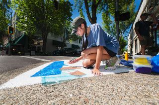 Rusty Rae/News-Register##Recent McMinnville grad Natalie Connolly paints a “We Can Do It!” image at Third and Ford streets. Connolly was one of a number of artists who created sidewalk images on June 21.