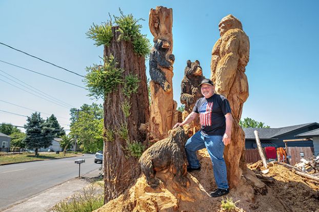 Rusty Rea/News-Register##Jesse Everett was wondering what to do with the four trunks of the tree he had to cut down — and carver Reid Phillips was looking for a project. The result is stopping traffic along Northeast 27th Street as drivers pause to appreciate the work.