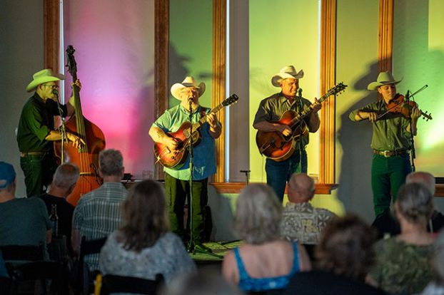 Rachel Thompson/News-Register##The Western Flyers swing shadows onto the wall and window blinds as they perform for a large crowd July 10 at The Grand. From left are bass player Matthew Mefford, guitarist Redd Volkaert, guitarist Joey McKenzie and fiddler Ridge Roberts.