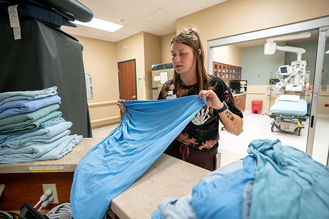 Rachel Thompson/News-Register##Certified Nursing Assistant Emma Hall restocks linens in the emergency room between rounds of helping with patients. Hall first visited the ER as a patient, and that inspired her to work in health care herself.