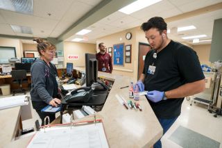 Rachel Thompson/News-Register##Charge nurse Jenny Root, left, who was overseeing the ER the night of July 17, talks with Connor Smith, RN, right, one of the nurses on the overnight shift. In the background is Willamette Valley Medical Center’s ER director, Brandon Harris, also a nurse.