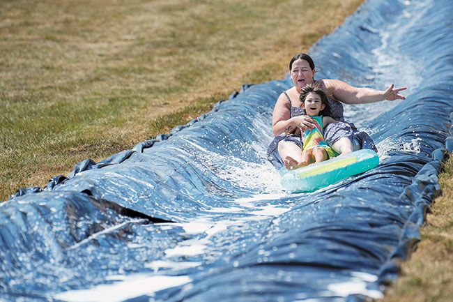 Rachel Thompson/News-Register##Becky Stanford of McMinnville and her 4-year-old daughter, Dakota Barnes, rip downhill on a water slide at Rock of Ages. Families also enjoyed collecting candy from a radio-controlled bomber and other activities during Saturday’s Fun Festival.