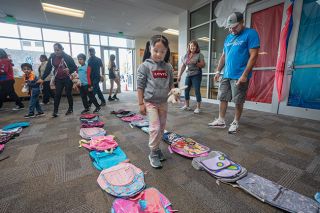 Rachel Thompson/News-Register##First-grader Elizabeth Serato Lara, holding a stuffed rabbit she received from Juliette&rsquo;s House, thinks hard before selecting a backpack from the display at Beyond Backpacks Saturday. &ldquo;Whether it&rsquo;s princesses or Elsa or Minecraft,&rdquo; or just a plain one, getting to choose means a lot to children, said Debbie Beam, a volunteer.