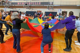 Starla Pointer/News-Register##McMinnville school employees practice teamwork as they play a game with parachutes, trying to bounce a ball from one chute to the other, at the district-wide welcome back event Wednesday in the Mac High gymnasium. More than 800 teachers, assistants, secretaries, custodians and other workers are preparing for the first day of classes in the district on Monday.