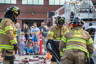 Rachel Thompson/News-Register##Crowd of children and adults at the McMinnville Fire District 150th anniversary event Sunday watch as firefighters Israel Pintor, left), Ryan Zollinger and Taylor Holt perform an extrication demonstration using a hydraulic rescue tool known as Jaws of Life.