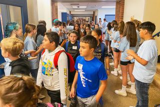 Starla Pointer/News-Register##New sixth-graders flow down the hallway on the way to an assembly in the gym Monday morning, the first day of classes at Patton Middle School. Eighth-grade Mustang Mentors applaud as they pass. Sixth-graders at Patton and Duniway middle schools had a few hours to get to know their buildings before seventh- and eighth-graders arrived.