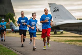 Rachel Thompson/News-Register##With Evergreen planes as a backdrop, Scott Kirkland, left, from Amity, and Julian Reyes, age 12, and his father, Beto Reyes of McMinnville, make their way along the scenic Champions Run course.