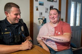 Rusty Rae/News-Register##Lexie Denman happily shows Carlton Police Officer Tim Jordan her latest tattoo, which she had done in his honor as well as in celebration of her success in dealing with anxiety and depression. The tattoo includes his call number, 873, along with the words, “To the one who saved me,” in recognition of the day she hit bottom and he talked her into getting help.