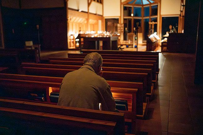 Rachel Thompson/News-Register##Lights are used in the altar but the rest of the sanctuary remains dark; retreatant Jim Foglio follows the liturgy with help of a pew light.