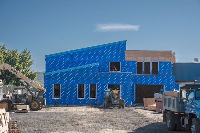 Rachel Thompson/News-Register##Crews are preparing to ‘dry-in’ the future middle school building, now wrapped in distinctive blue moisture barrier. Work is on schedule with the middle school structure as well as the new high school gym.