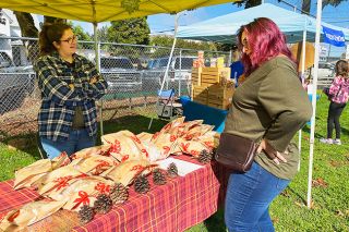 Starla Pointer/News-Register##Baker Nickole Lee of Emerald Goods talks about her bread with customer Theresa Davis at the Lafayette Harvest Fest Saturday. It was Lee’s first time selling at a festival; she said she tried it because she grew up in Lafayette before moving to Newberg. She usually sells her sandwich breads and flavored loaves, such as fall spice, through her Facebook page. Lee said she started her bakery because she enjoys baking, especially making bread.