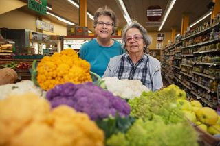 Rusty Rae/News-Register##Kristen Schofield and Susan Sanford with some of the colorful cauliflower their store, Harvest Fresh Grocery and Deli, is carrying this fall — purchased from a local farmer who’s been supplying the store since the women bought it 30 years ago. In addition to produce, the Third Street store carries groceries, bulk foods, wine, vitamins and supplements and prepared food in its deli.