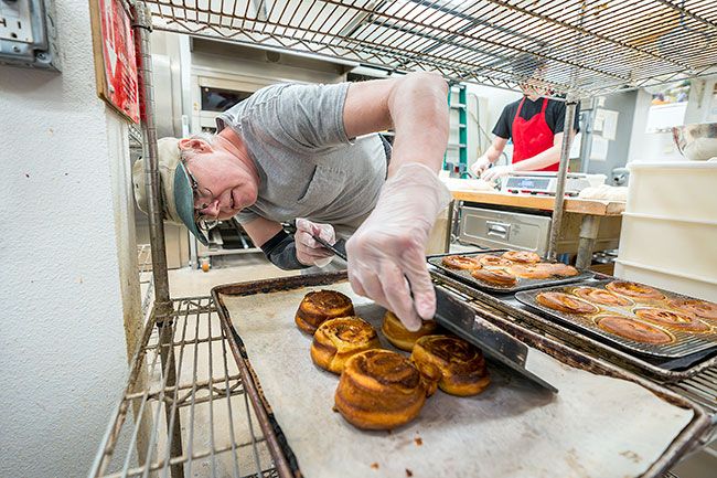 Rachel Thompson/News-Register##David Boone gently loosens sticky cinnamon rolls that have just come out of the oven and are ready for the cooling rack. He and other bakers prepare numerous types of pastries and breads for the bakery in the wee hours of the morning.