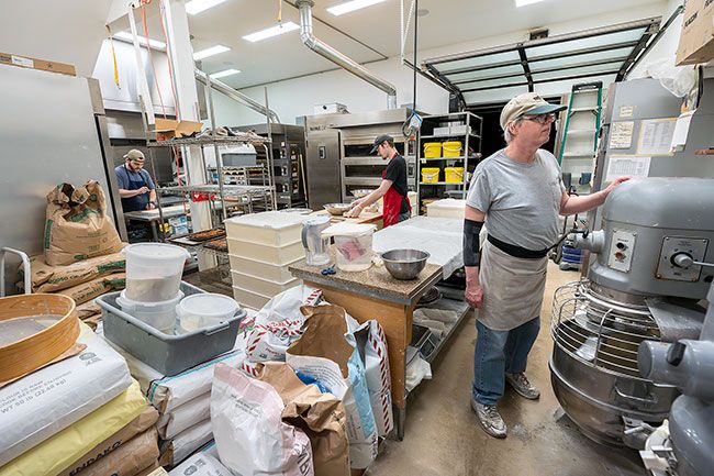 Rachel Thompson/News-Register##David Boone, right, waits as eggs and butter are beaten in a huge Hobart mixer. He will add flour to make a brioche dough. In the background, Iain Danicic, left, works on croissants, and Gavin Nelson, center, portions dough.