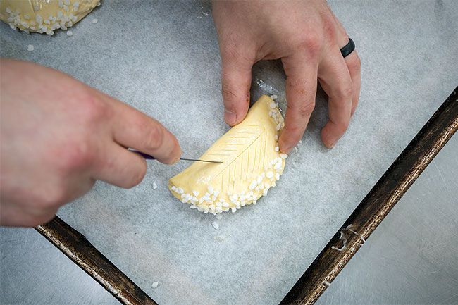 Rachel Thompson/News-Register##Danicic pierces an apple turnover, called a chausson aux pommes, in preparation for putting it into a hot oven about 5:40 a.m.