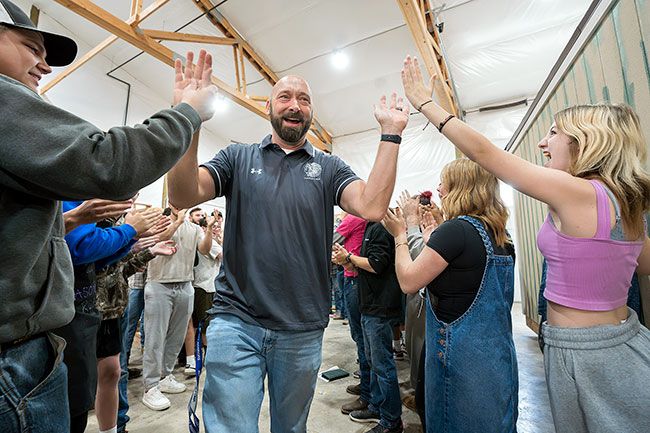 Rachel Thompson/News-Register##Amity High School CTE teacher John Stearns high-fives some of his students, who formed a gauntlet to congratulate him on being one of 25 trades teachers in the nation to win $50,000 — $35,000 for their schools and $15,000 for themselves. Stearns was completely surprised by the announcement.